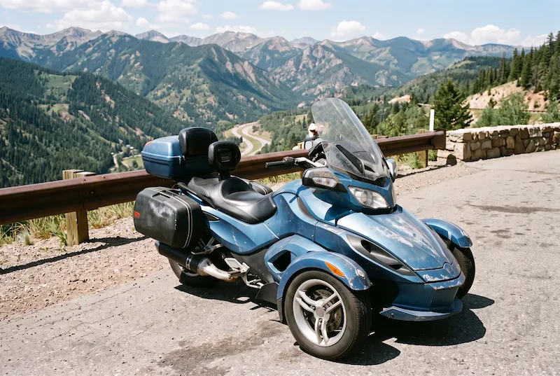 Older touring three-wheeler with sun-dulled, chipped body panels parked at a highway pullout
